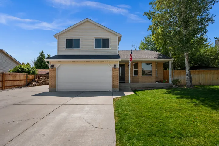 Two-story residence featuring a two-car garage, brick facade accents, a covered front porch, and a bay window
