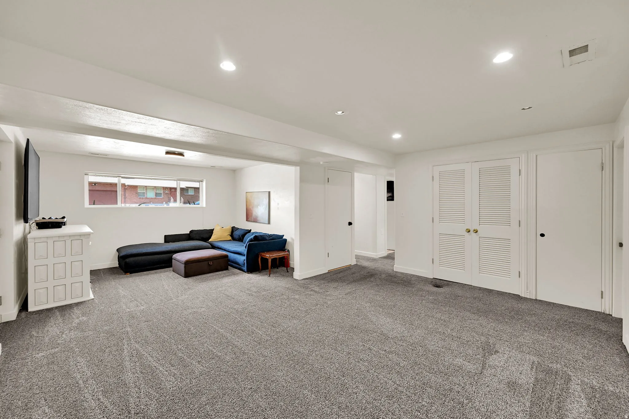 Recessed lighting illuminates the carpeted flooring and white walls
