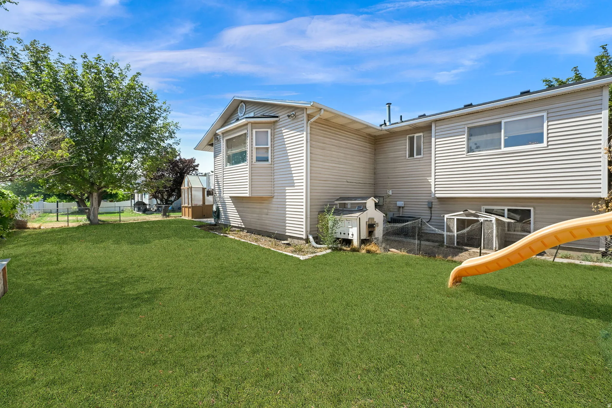 Expansive backyard featuring a meticulously manicured lawn, mature shade trees, and established landscaping