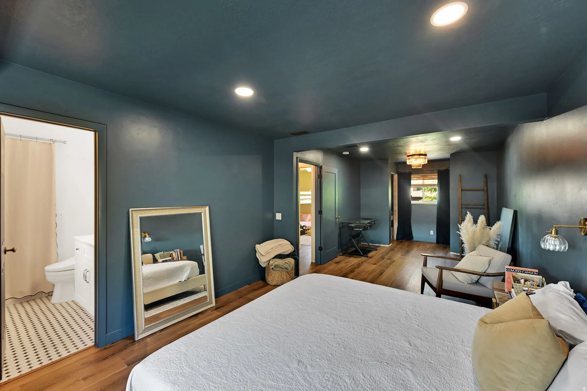 Wood-finish flooring throughout, recessed lighting, and an attached bathroom featuring a mosaic tile floor