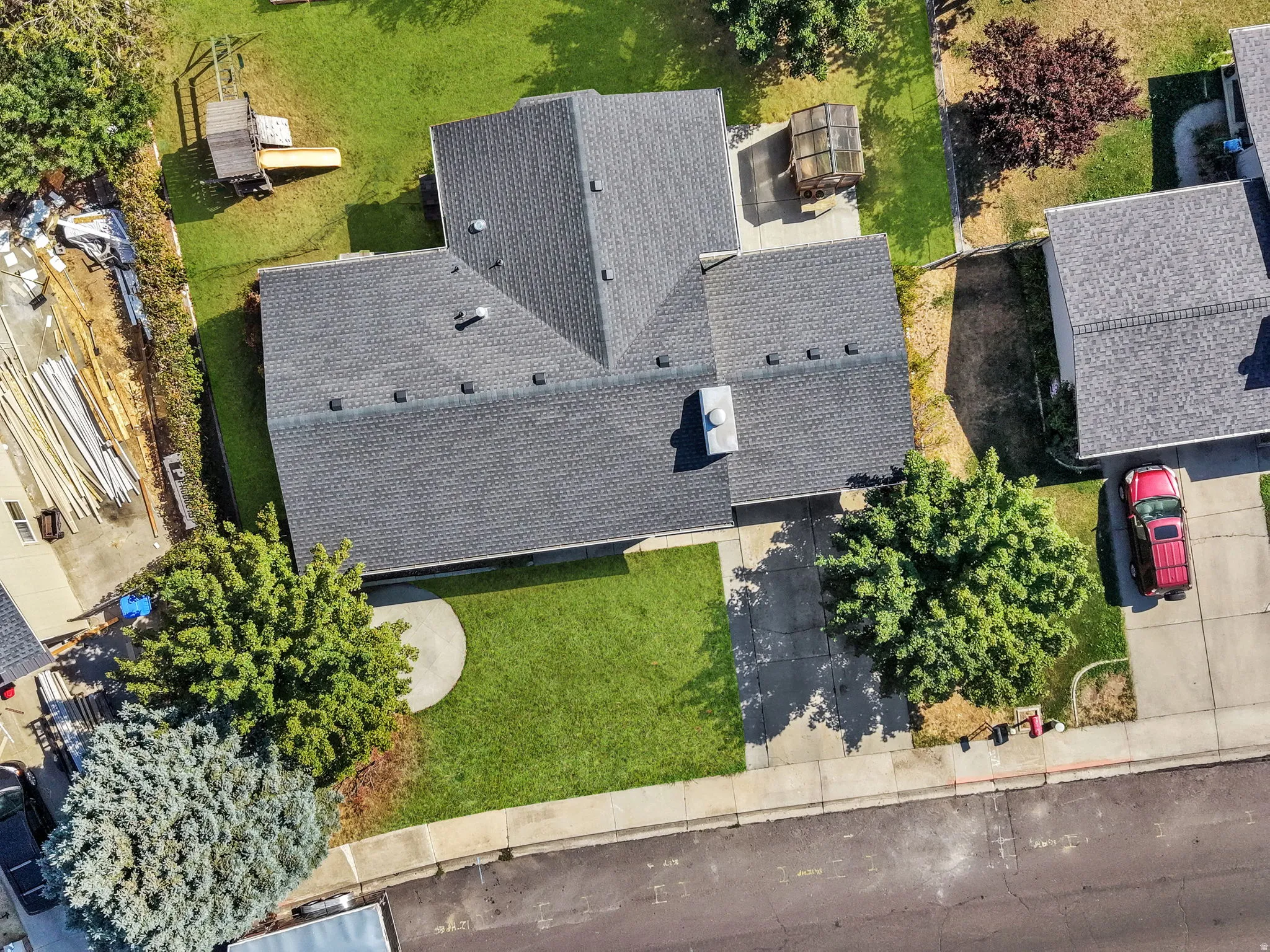 Aerial view showcasing a multi-level home with steeply pitched rooflines and composite shingle roofing