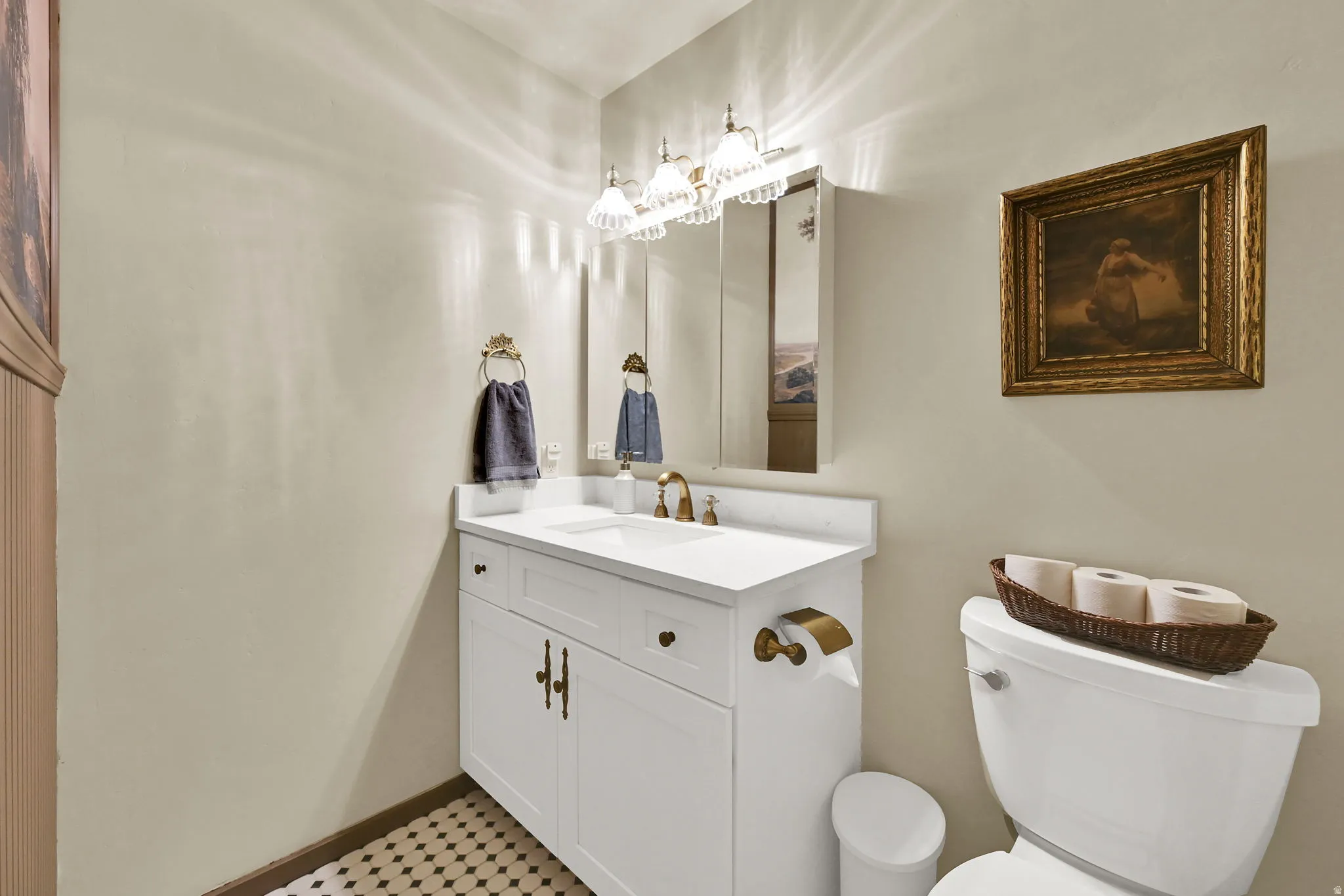 White vanity with a single basin, brass-finish faucet, and coordinating hardware