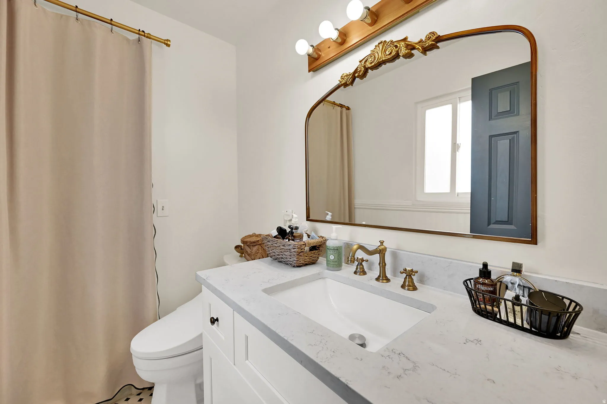 White floating vanity with quartz countertop, undermount sink, and brass-finish fixtures