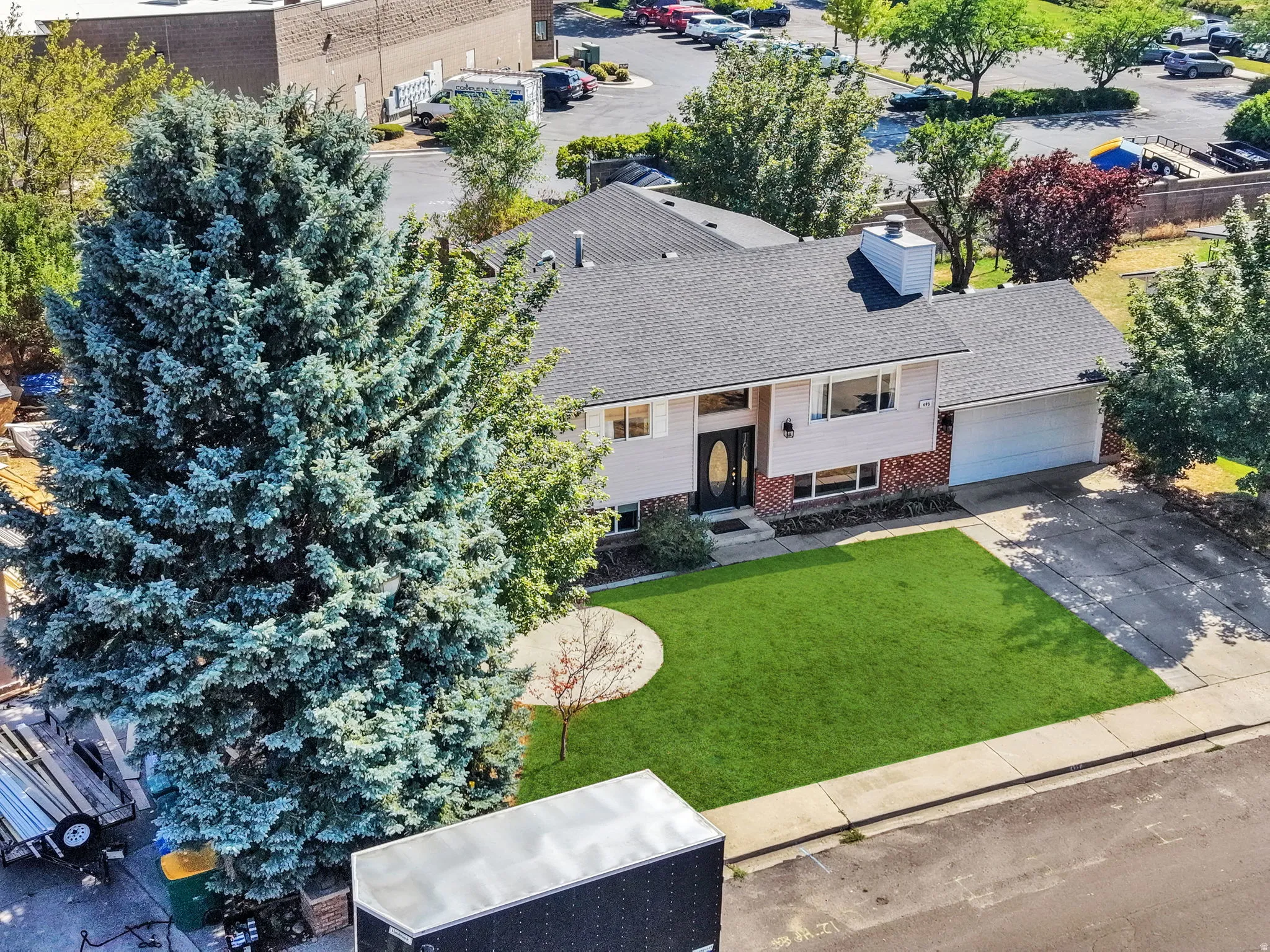 Charming single-story residence featuring a freshly manicured lawn, mature landscaping with evergreen trees, attached garage, front entry with brick detailing, and professional hardscaping throughout the property