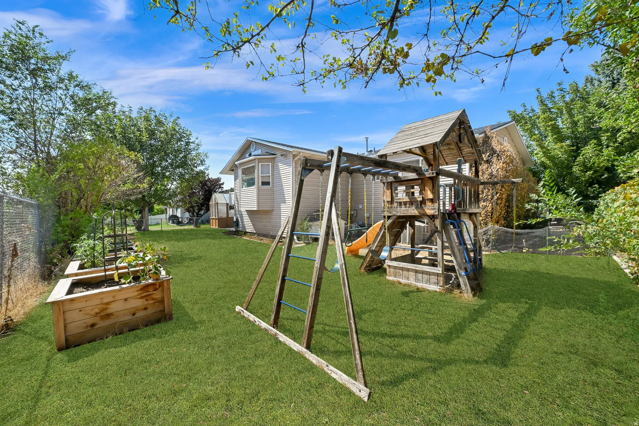 Expansive lawn area, raised garden bed, and mature perimeter trees