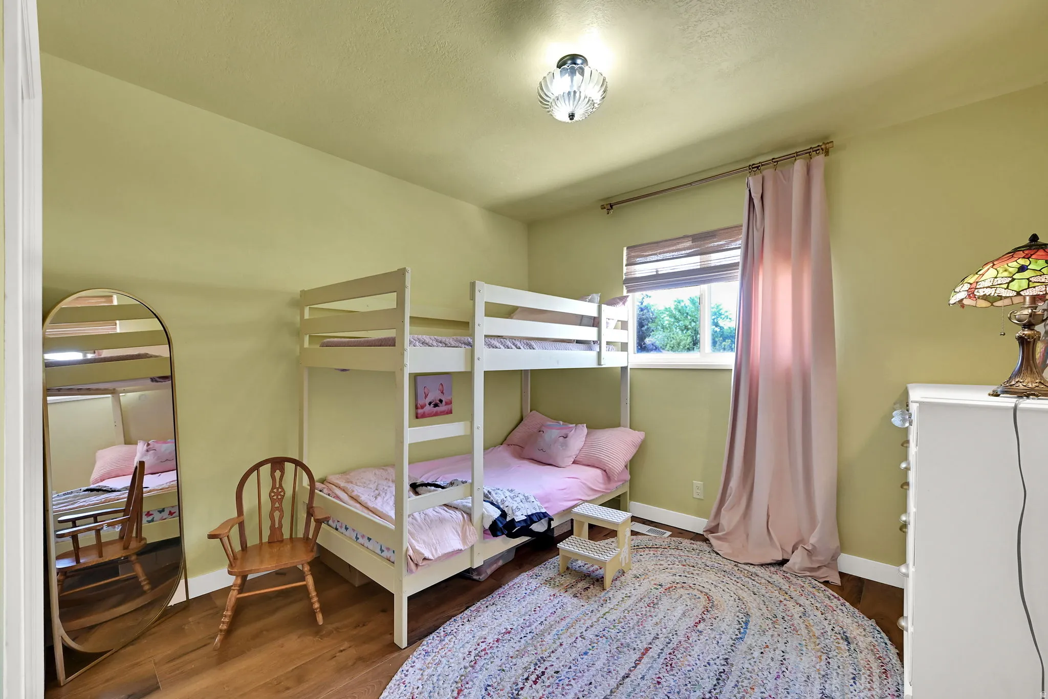 Bright bedroom with soft yellow walls and wood-finish flooring