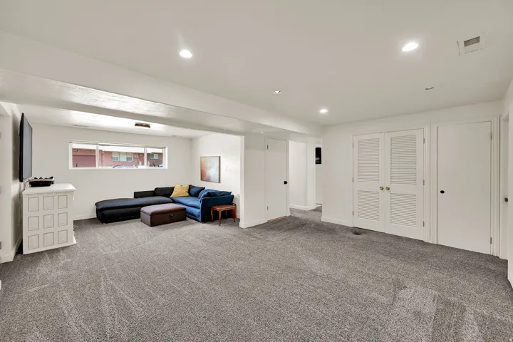 Recessed lighting illuminates the carpeted flooring and white walls