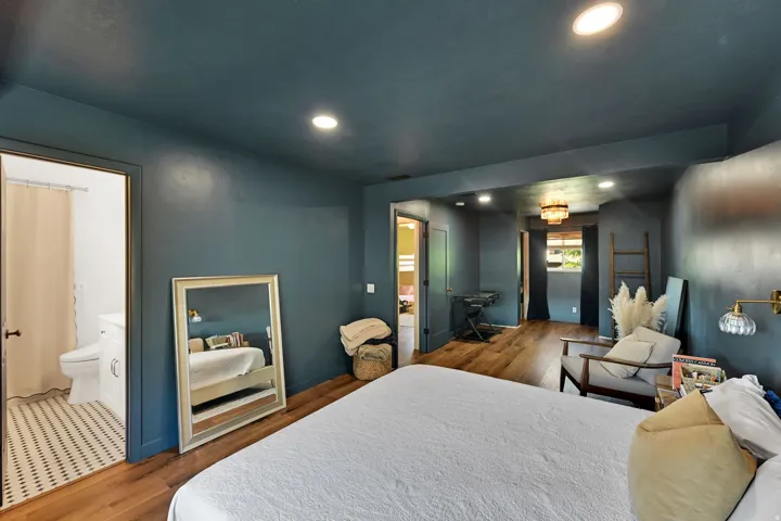 Wood-finish flooring throughout, recessed lighting, and an attached bathroom featuring a mosaic tile floor
