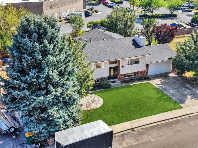 Charming single-story residence featuring a freshly manicured lawn, mature landscaping with evergreen trees, attached garage, front entry with brick detailing, and professional hardscaping throughout the property