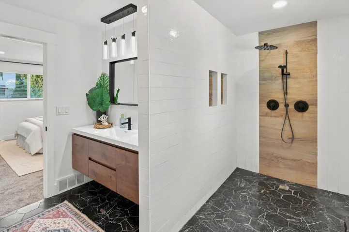 Floating wood-finish vanity with a vessel sink, a matte black faucet, and a wall-mounted rectangular mirror