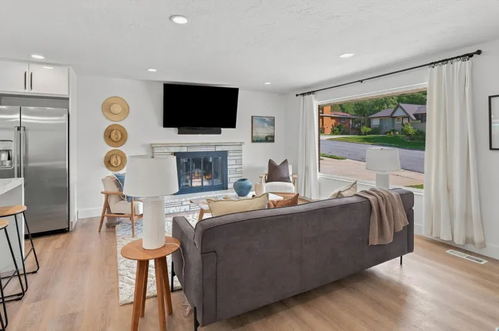 Open-concept living space with light wood-finish flooring, recessed lighting, and a wide window with a black curtain rod