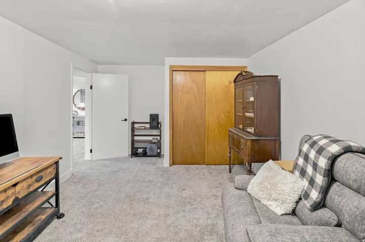 Carpeted flooring, white walls, and a built-in closet with wood-finish sliding doors