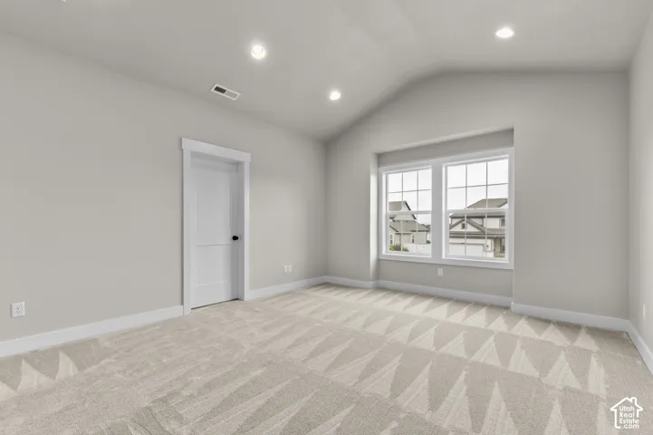Vaulted ceilings, neutral carpeting, recessed lighting, and double-pane windows with grid detailing