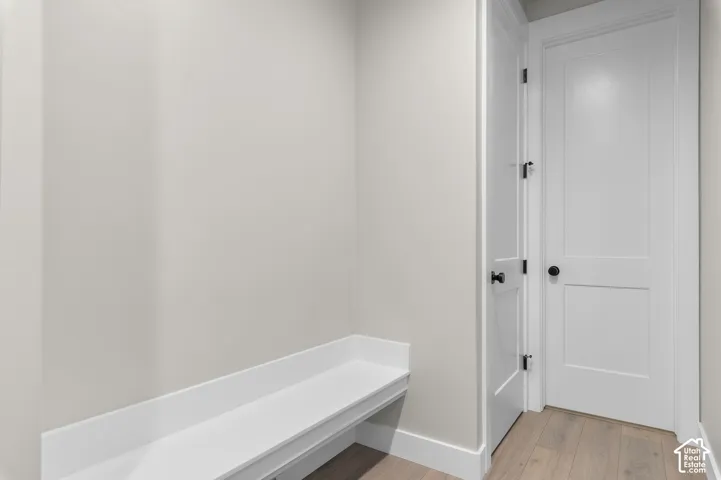 Built-in white bench seating, wood-finish flooring, and two-panel shaker-style interior doors featuring matte black hardware