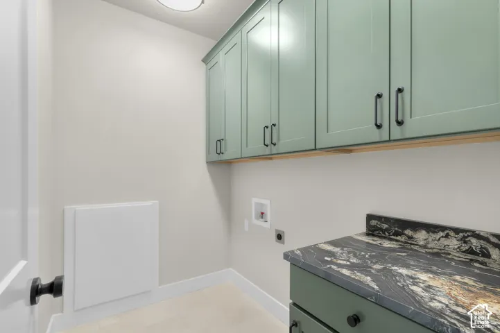 Utility room featuring green cabinetry, stone-finish countertops, matte black hardware, and integrated wall paneling