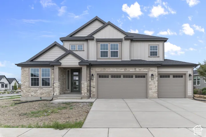 Two-story exterior featuring a mix of stone veneer and board-and-batten siding, a three-car garage, and a covered front entry