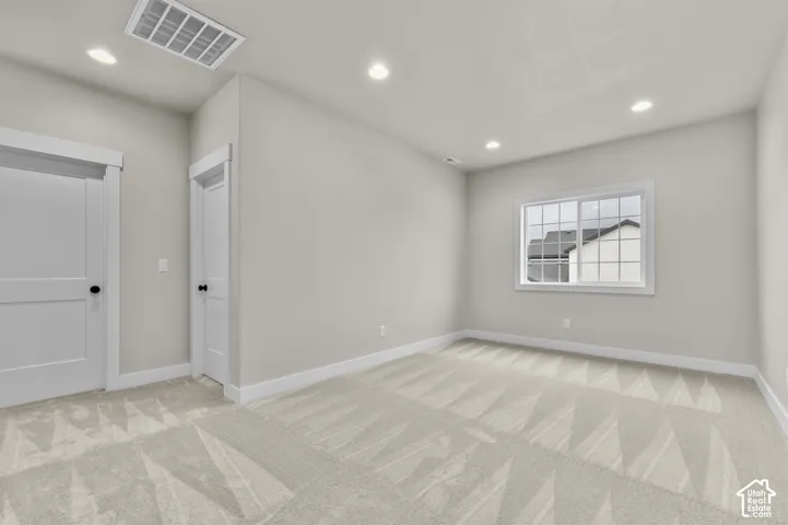 Interior room featuring neutral wall paint, wall-to-wall carpeting, recessed ceiling lighting, a multi-pane sliding window, and two paneled interior doors with matte black hardware