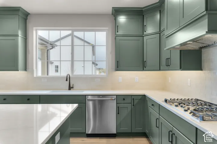 Kitchen featuring matte green shaker-style cabinetry, white quartz countertops, subway tile backsplash, stainless steel dishwasher, and built-in gas cooktop