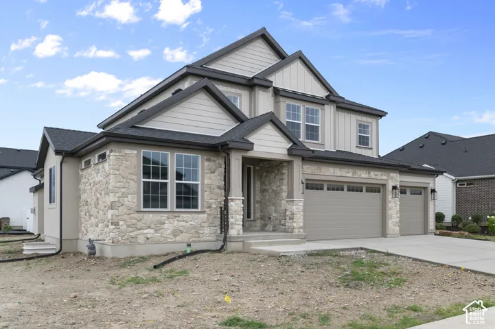 Multi-level exterior featuring stone veneer accents, mixed horizontal siding and board-and-batten siding, asphalt shingle roofing, and an attached three-car garage