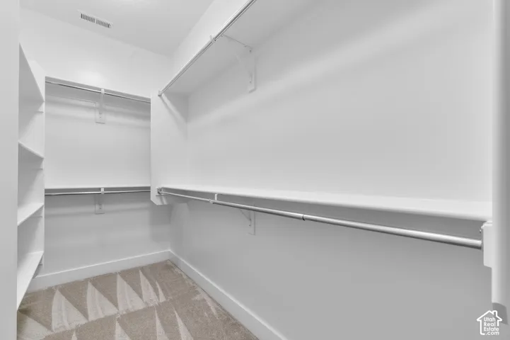Walk-in closet featuring white wall-mounted shelving and integrated metal hanging rods