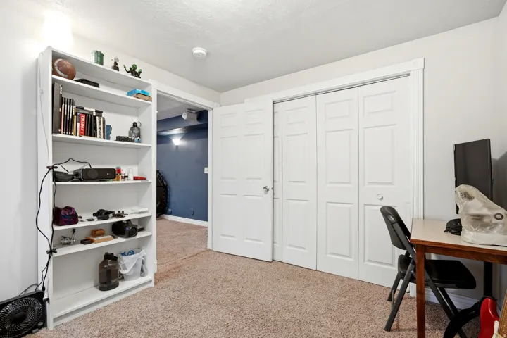Carpeted flooring with white bi-fold closet doors, white trim, and a built-in white shelving unit