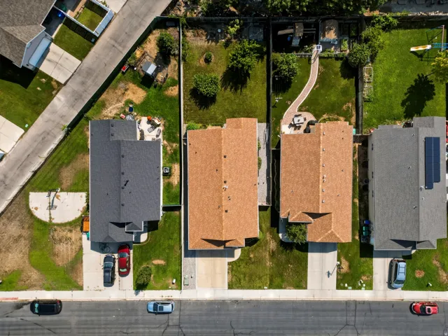 Aerial view showcasing four residential properties with distinct roof finishes—including clay tile and architectural shingle options—each featuring manicured lawns, mature landscaping, and individual driveways with street frontage