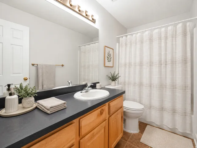 Warm wood-finish cabinetry with a dark countertop and integrated sink AI staged