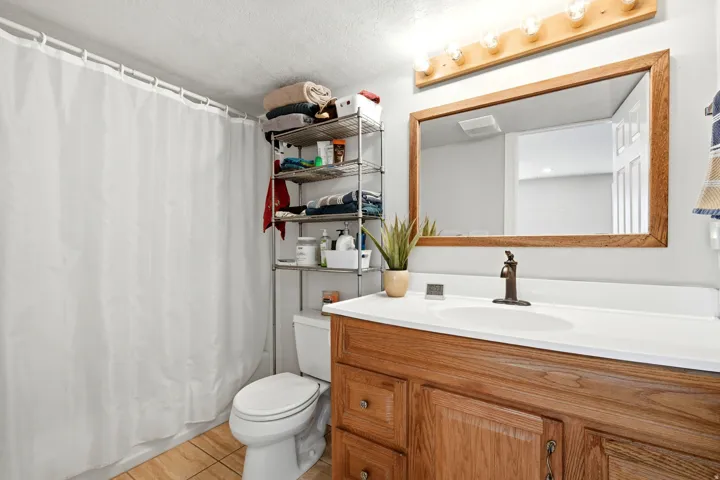 Bathroom featuring a wood-finish vanity with a white countertop and integrated sink, bronze-finish faucet, and a large wood-framed mirror