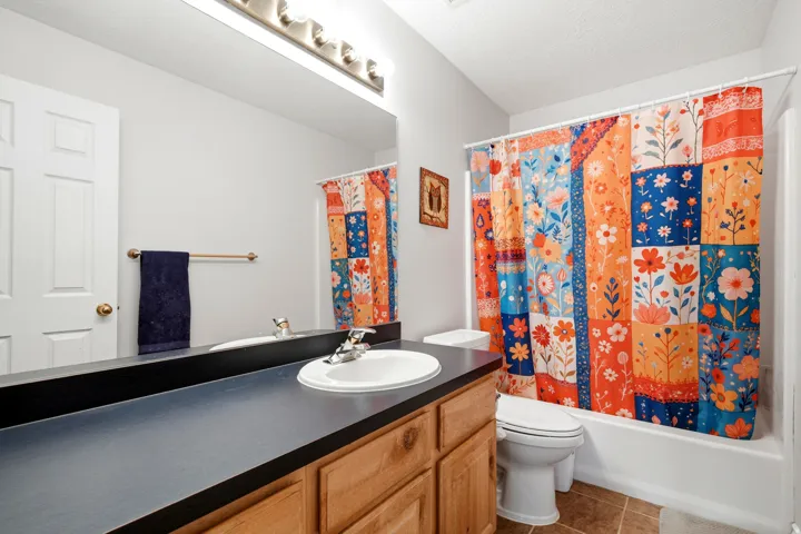 White vanity with integrated sink, wood-finish cabinetry, and dark countertop