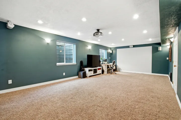 Spacious room with recessed lighting, integrated projector, and a large projection screen flex room, could be bedroom, office, theater