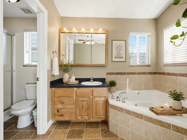 Wood-finish vanity with an integrated sink and dark countertop Primary AI Staged