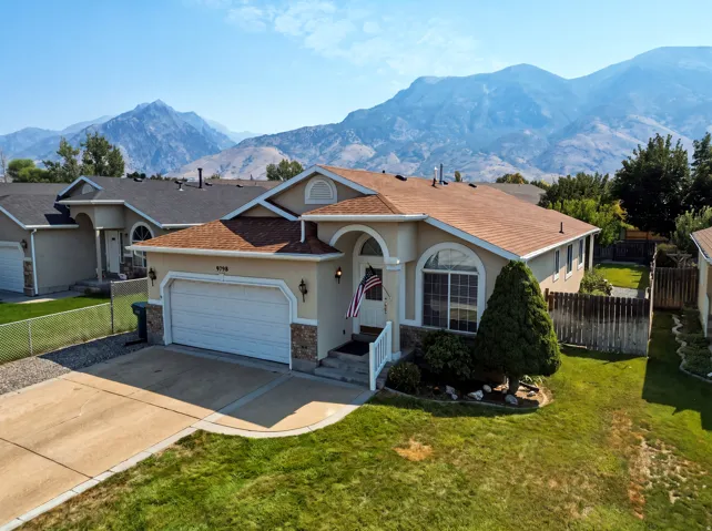 Stucco exterior with stone accents, arched entryway, attached garage, and a fenced backyard