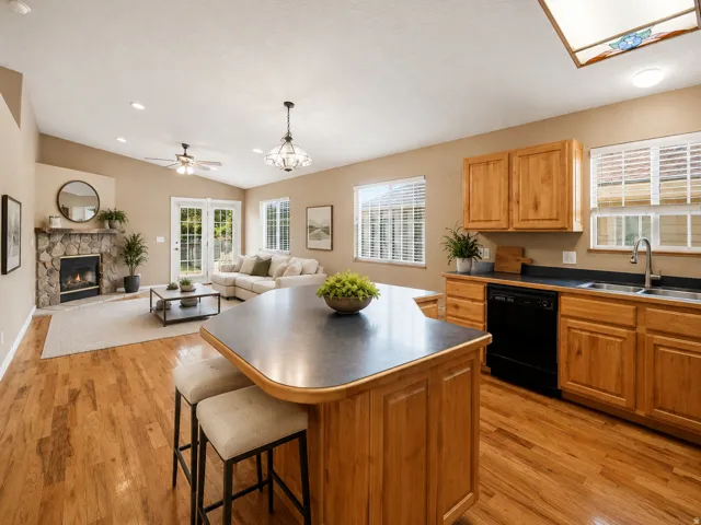 Open-concept kitchen and living area featuring wood cabinetry, stainless steel appliances, a large center island with seating, and wood-finish flooring throughout AI Staged