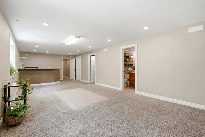 Recessed lighting, light-toned carpeting, a built-in bar, and a window
