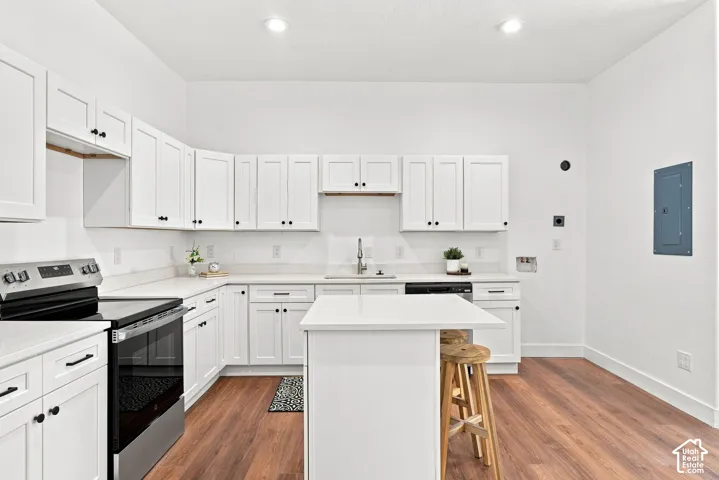 Modern kitchen featuring crisp white cabinetry with black hardware, stainless steel appliances including a gas range and built-in microwave, white subway tile backsplash, and a white quartz countertop island