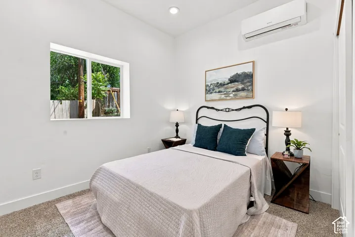 Recessed ceiling lighting, white walls, window, carpeted flooring, and a wall-mounted mini-split system