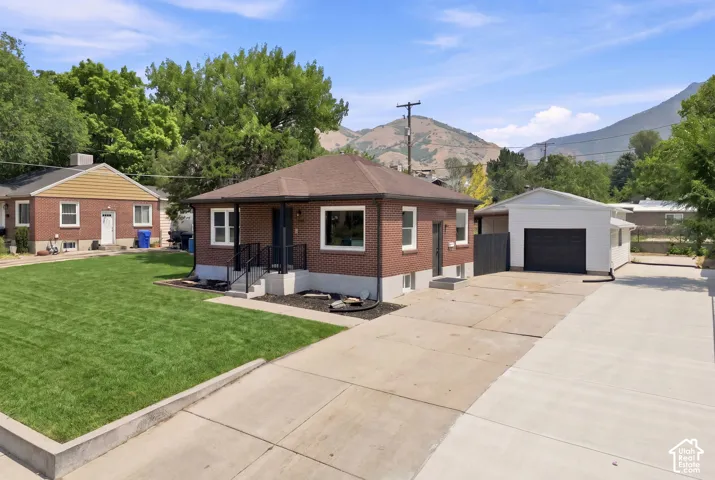 Brick exterior with white trim, covered front porch with black railings, attached two-car garage, and concrete driveway