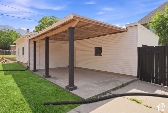 Covered concrete patio with white siding and black support columns