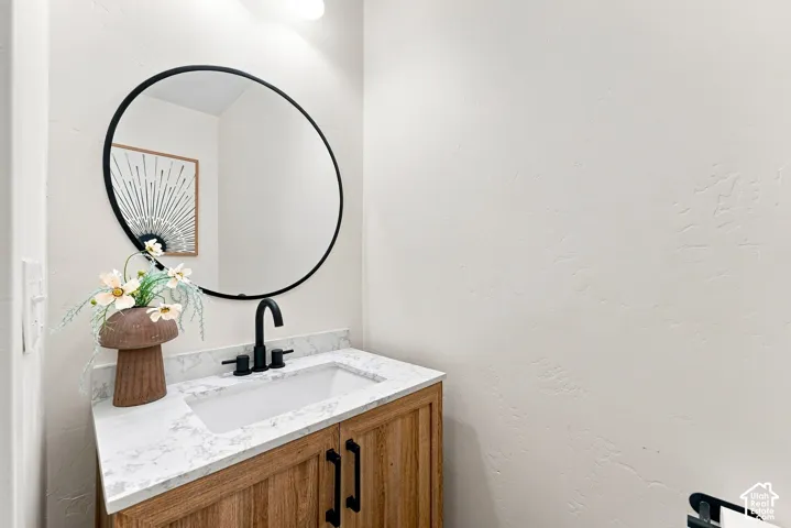 Elegant powder room featuring a wood-finish vanity with black hardware, white marble-look countertop, and integrated sink