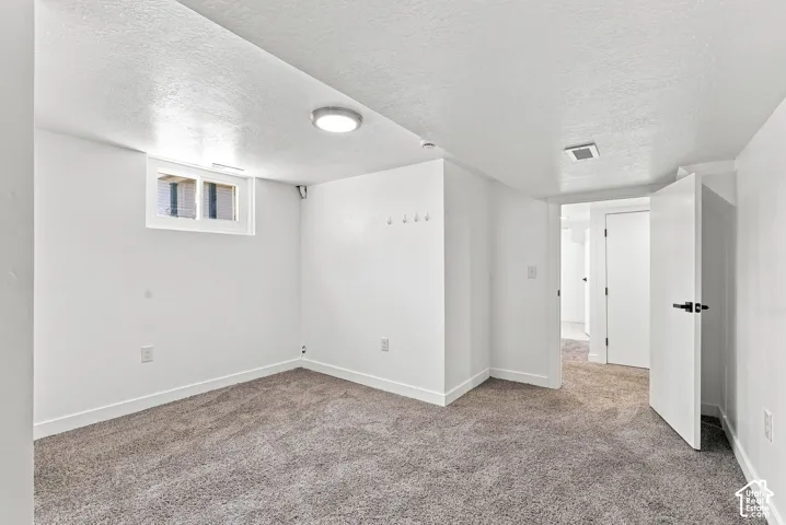 White walls with textured finish, light gray carpet flooring, white trim, recessed lighting, and a white window