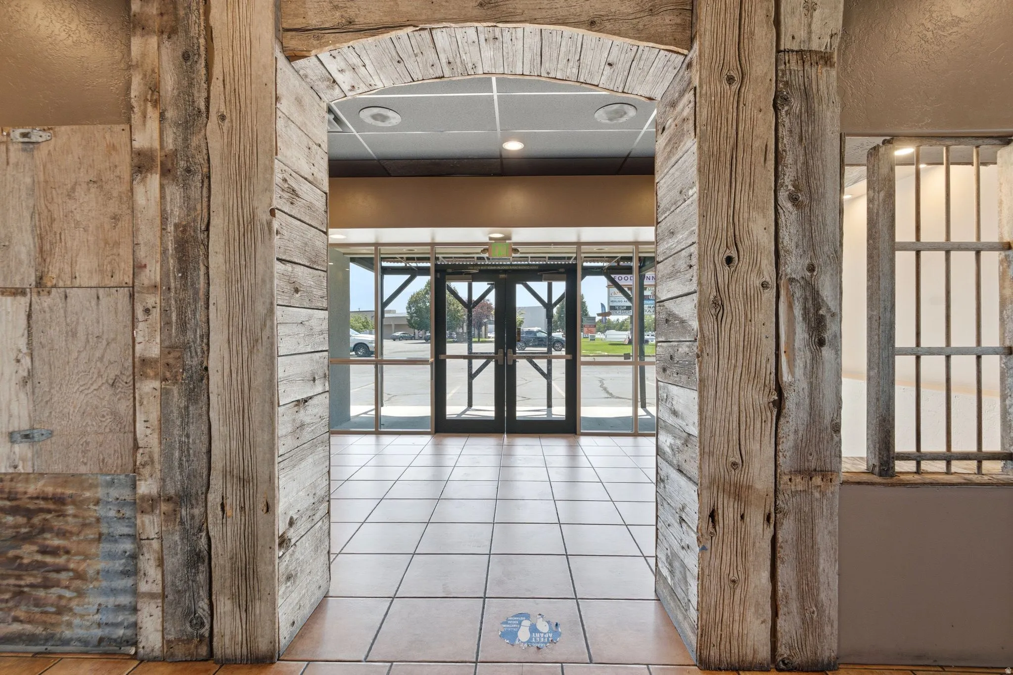 Rustic wood-paneled archway leading to an entry with glass doors