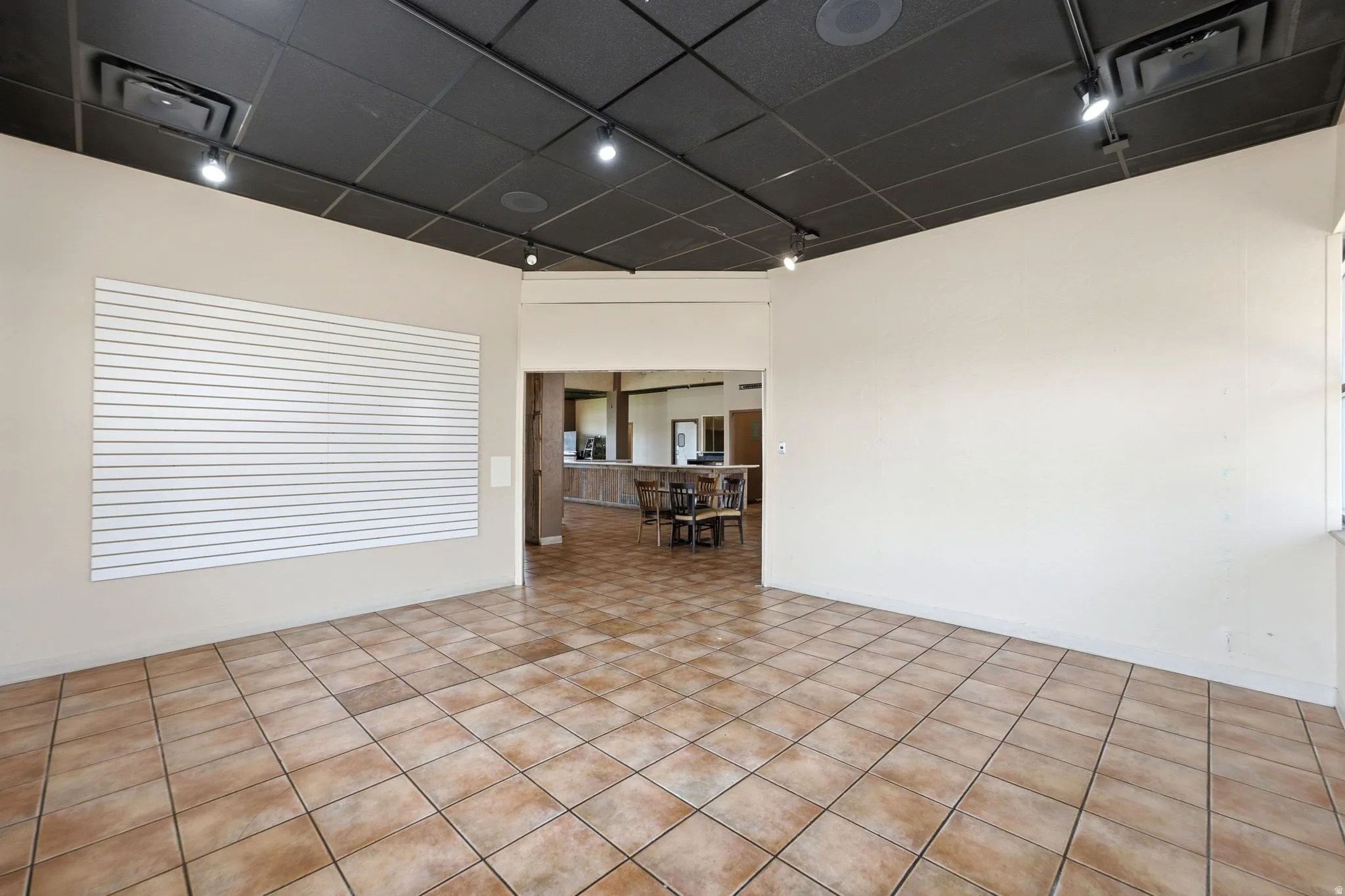 Spacious open room featuring diagonal-pattern ceramic tile flooring, recessed lighting throughout, and white painted walls