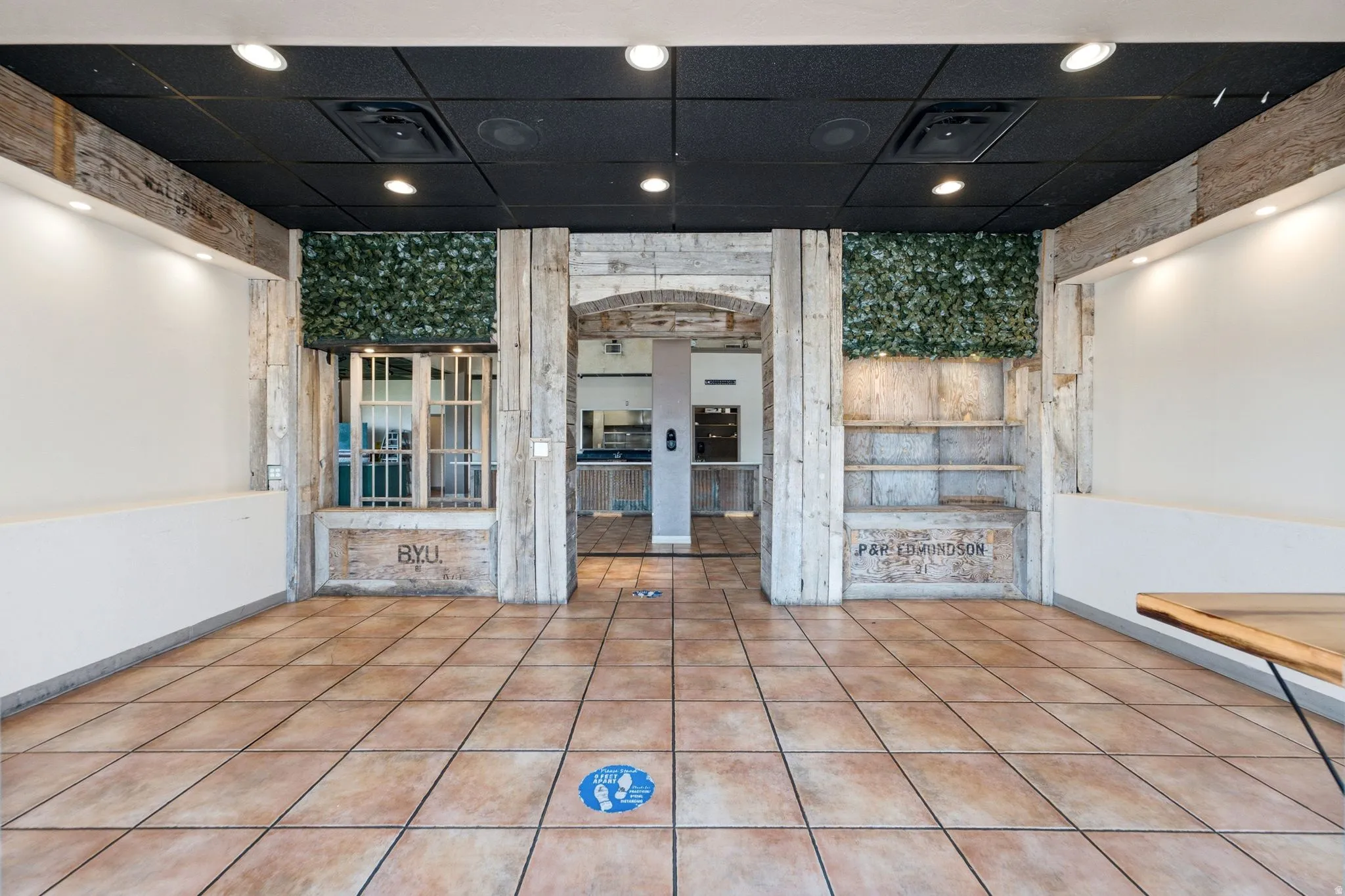 Tile flooring throughout with a black drop ceiling, recessed lighting, and exposed wood beams