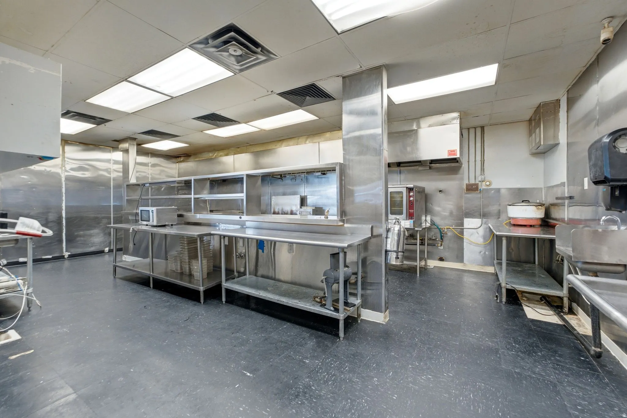 Stainless steel work surfaces, stainless steel shelving, built-in exhaust hood, and industrial flooring