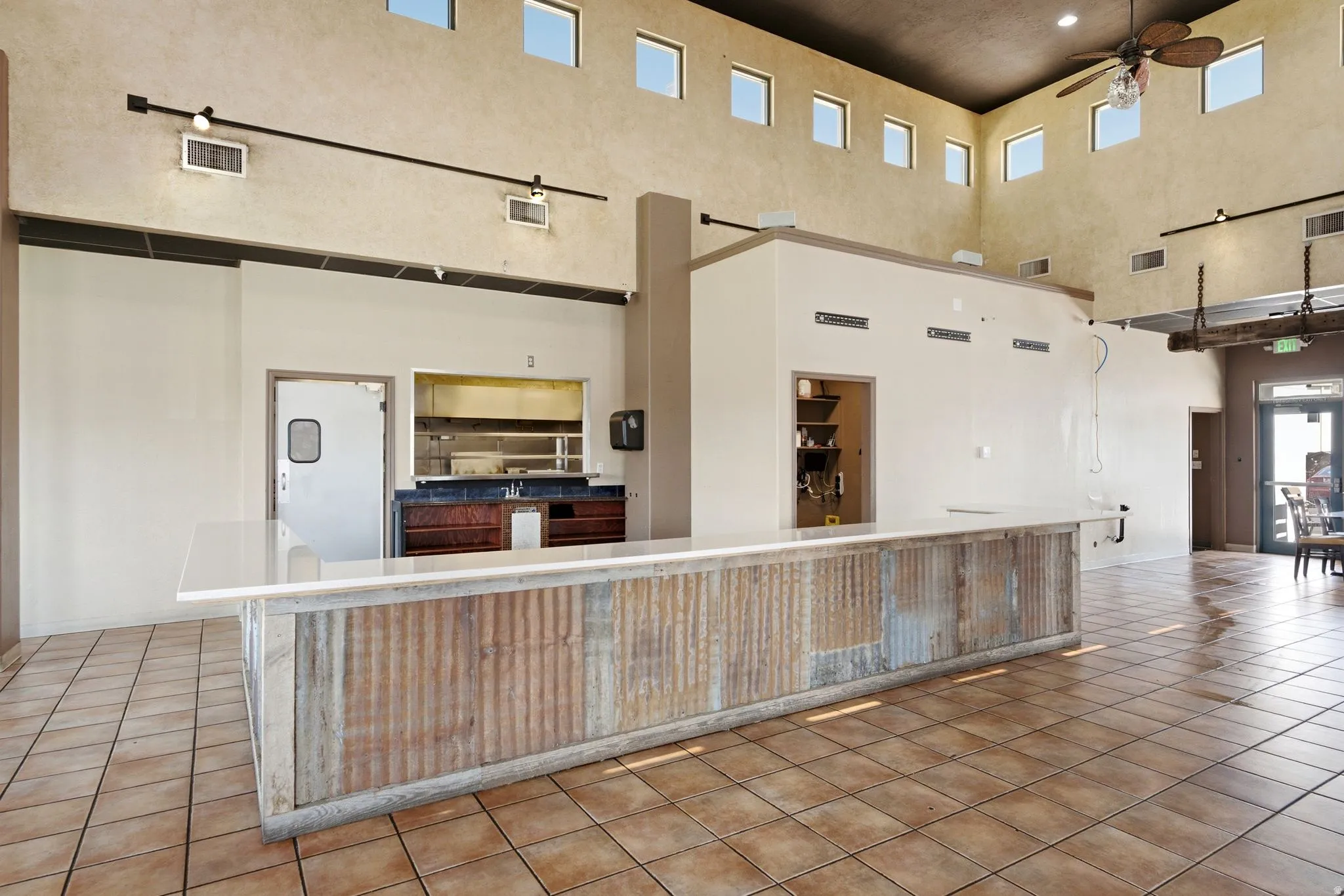 Corrugated metal bar with a light-toned countertop, tile flooring, and track lighting