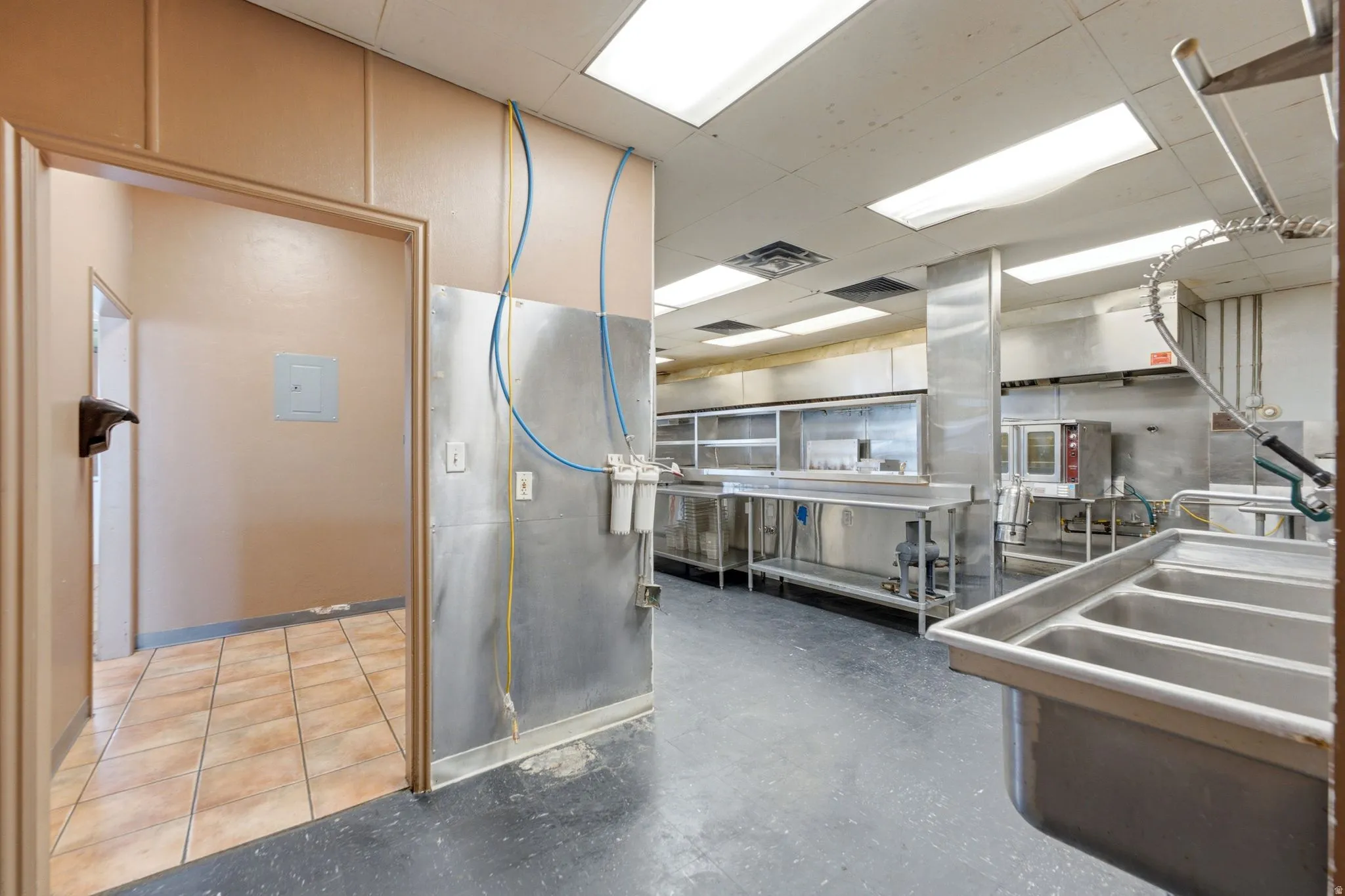 Commercial kitchen featuring stainless steel prep surfaces, professional-grade equipment layout, and ample counter workspace