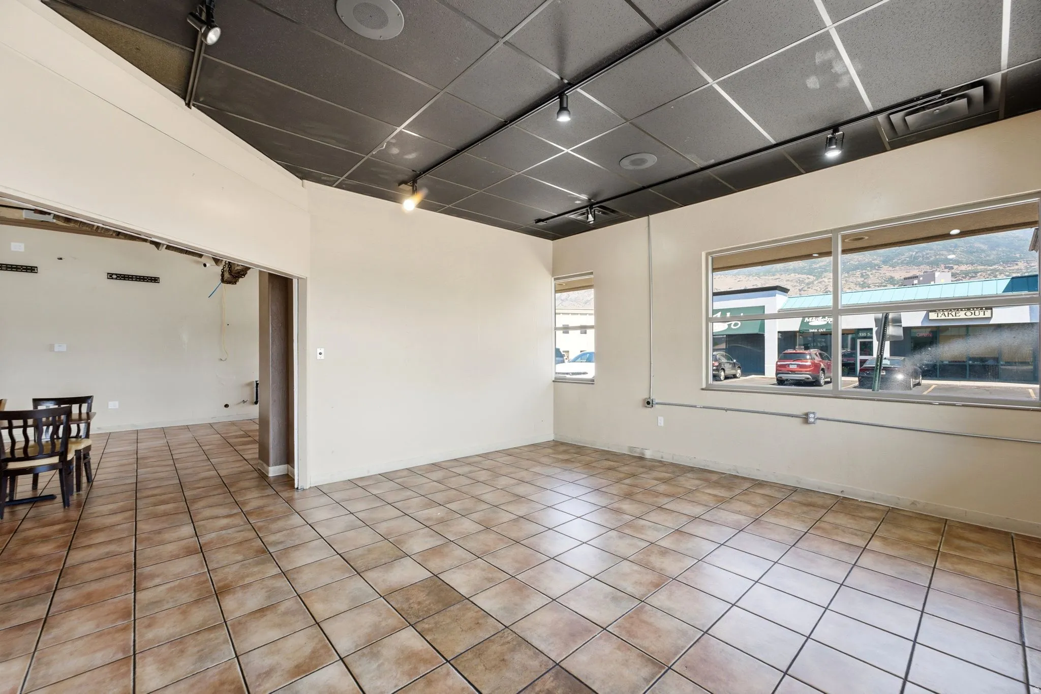 Bright, open commercial or retail space featuring tile flooring throughout, recessed ceiling lighting, and expansive front windows offering natural light and street visibility