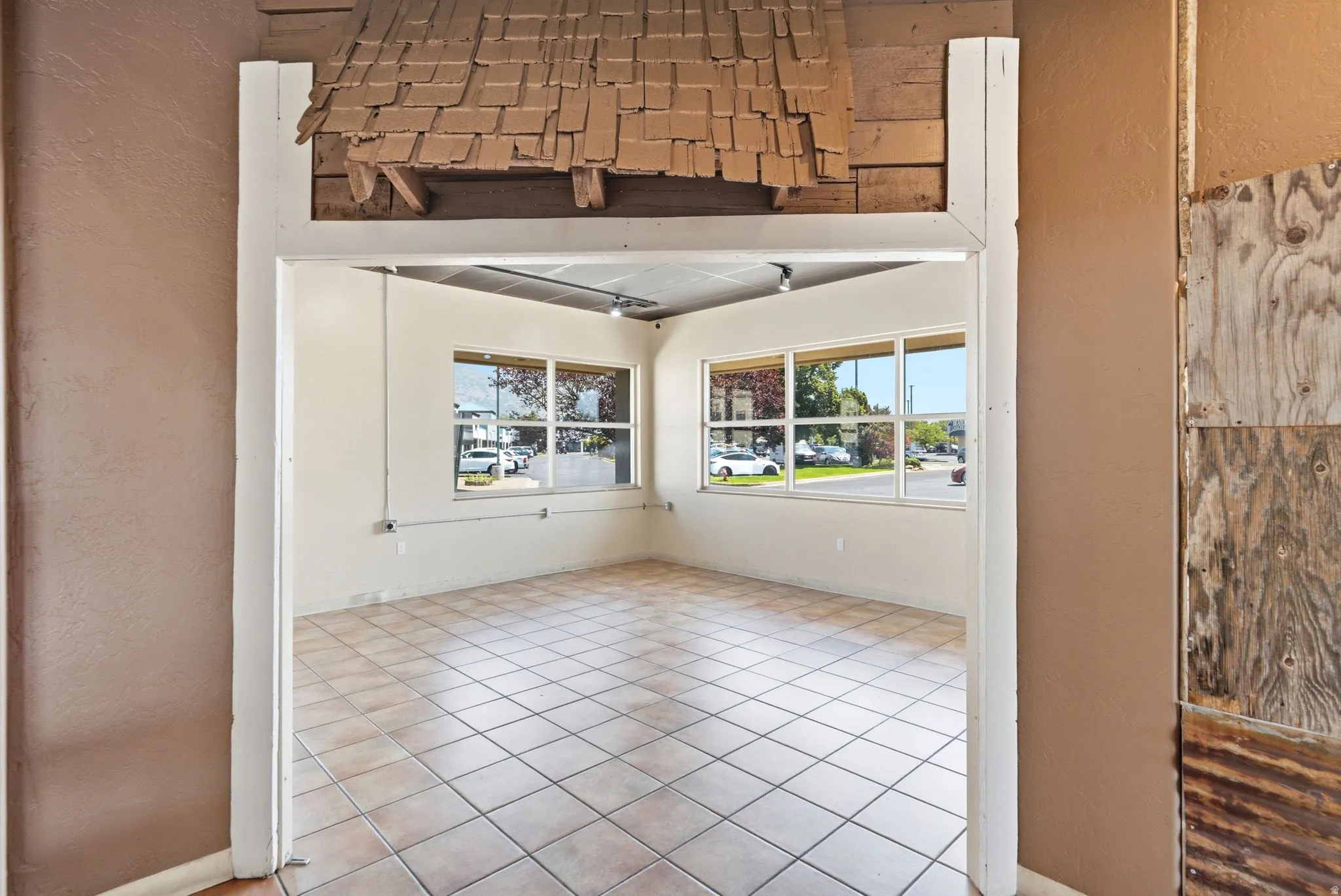 Bright corner retail or commercial space featuring expansive windows with natural light, neutral tile flooring, and clean white walls
