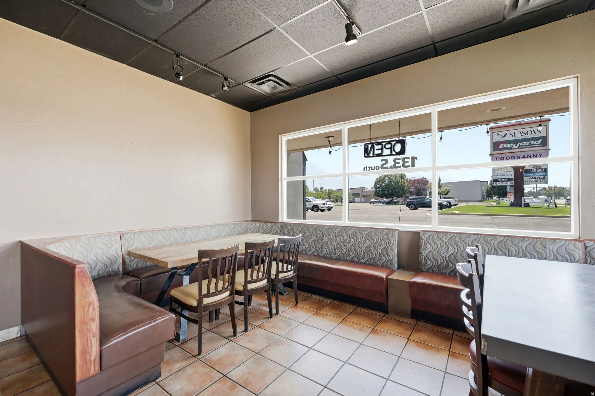 Spacious dining area featuring built-in booth seating with upholstered cushioning, wood-finish chairs, and tile flooring