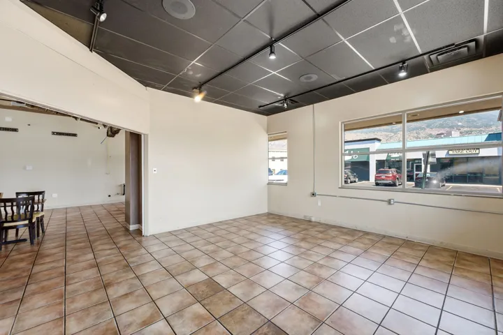 Bright, open commercial or retail space featuring tile flooring throughout, recessed ceiling lighting, and expansive front windows offering natural light and street visibility